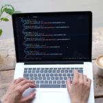 person using macbook pro on brown wooden table