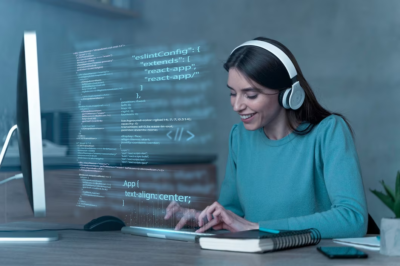 Woman at computer with headset typing code.